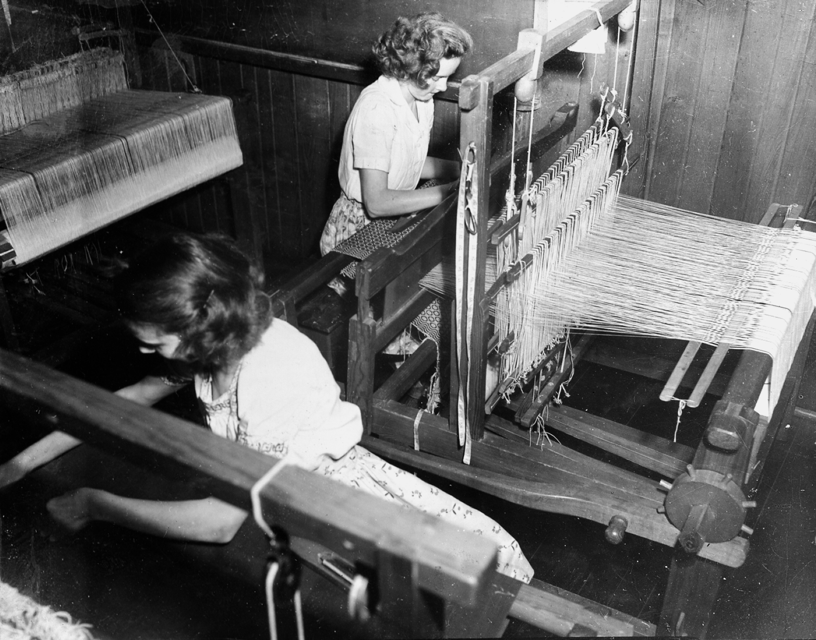 black and white photograph of women at their weaving looms.